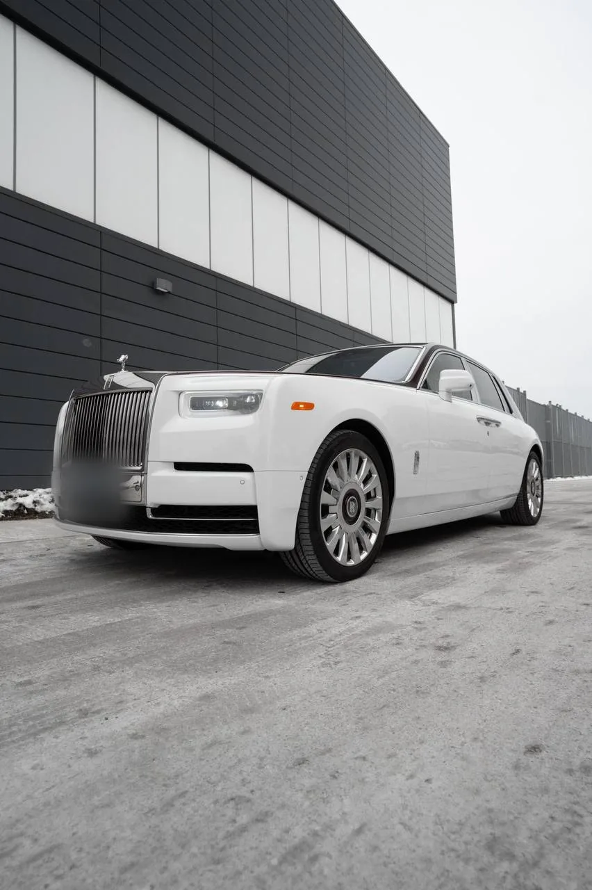 White Rolls-Royce Phantom parked beside a modern building
