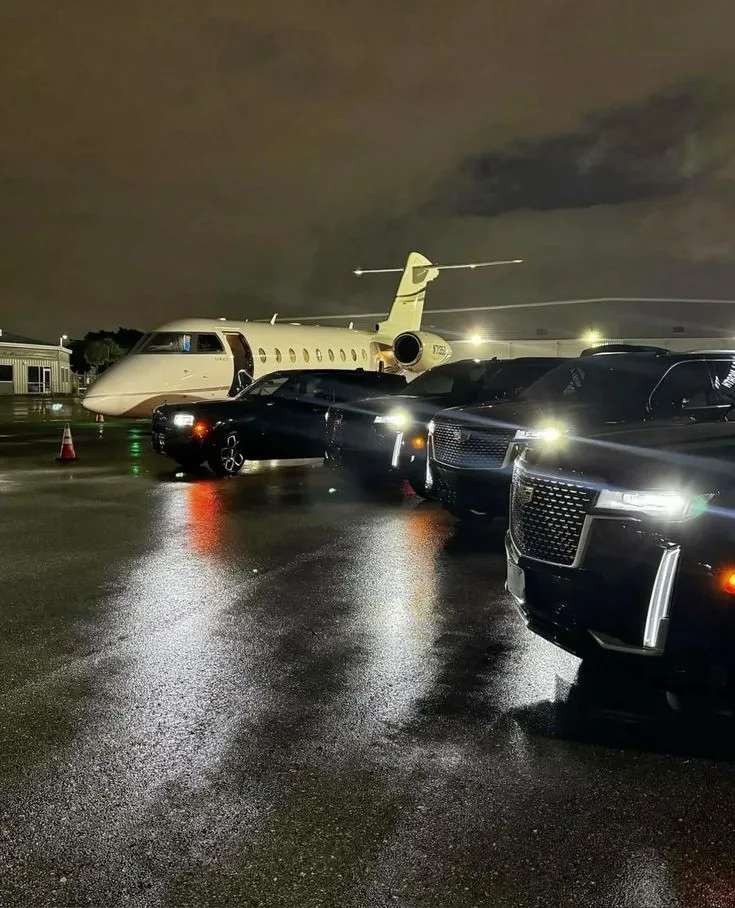 Black SUVs lined up on an airport apron at night